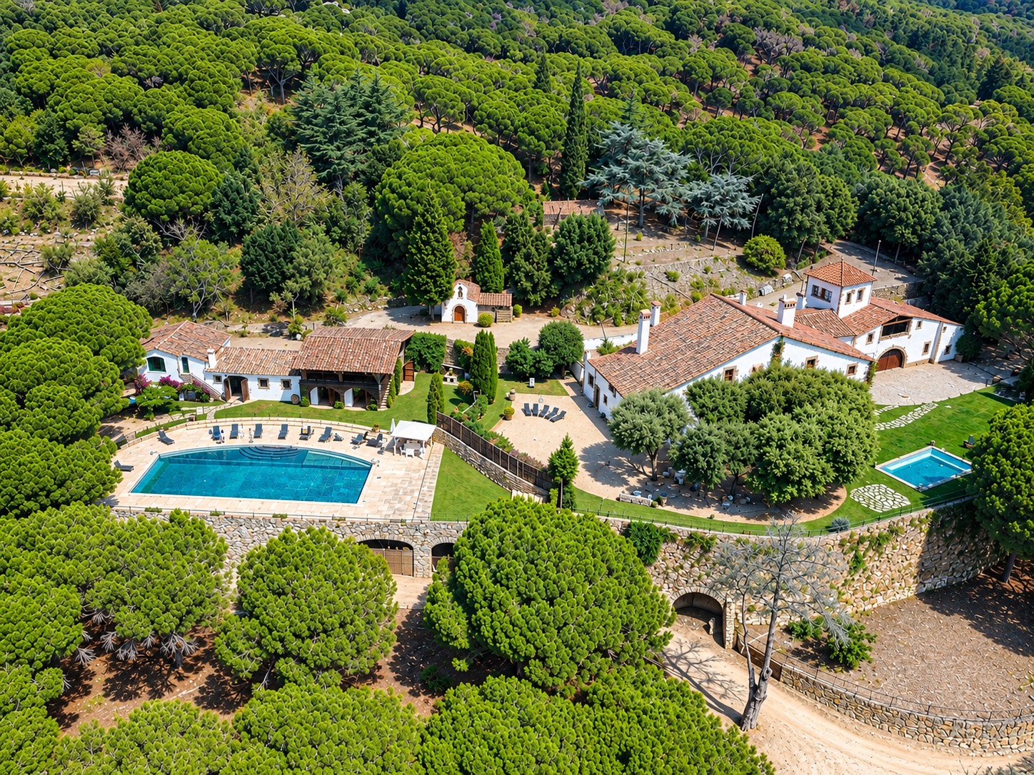 La finca sencera des de l'aire: les dues cases, l'ermita i les piscines entre la pineda